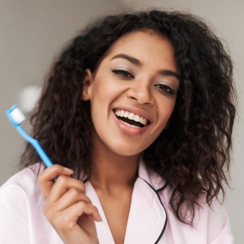 lady-sitting-on-bed-with-toothbrush-in-hand-and-M2E86QA-1.jpg